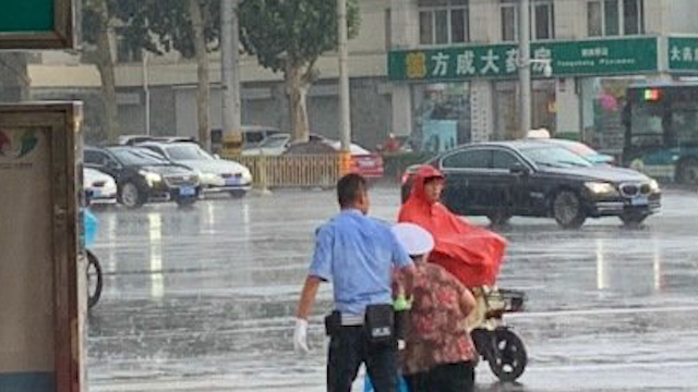 济南一辅警用警帽给老人遮雨还送她过马路 网友：必须严肃奖励他