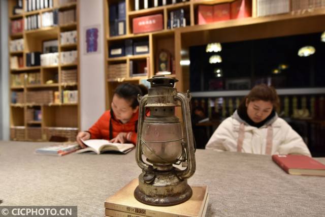 2018年1月10日,贵州省遵义市"红色书店",读者在一盏马灯旁阅读.