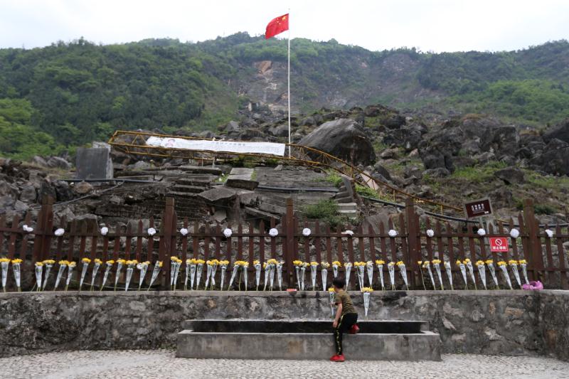 一个孩子向北川中学新区被山崩掩埋的遗址献花.