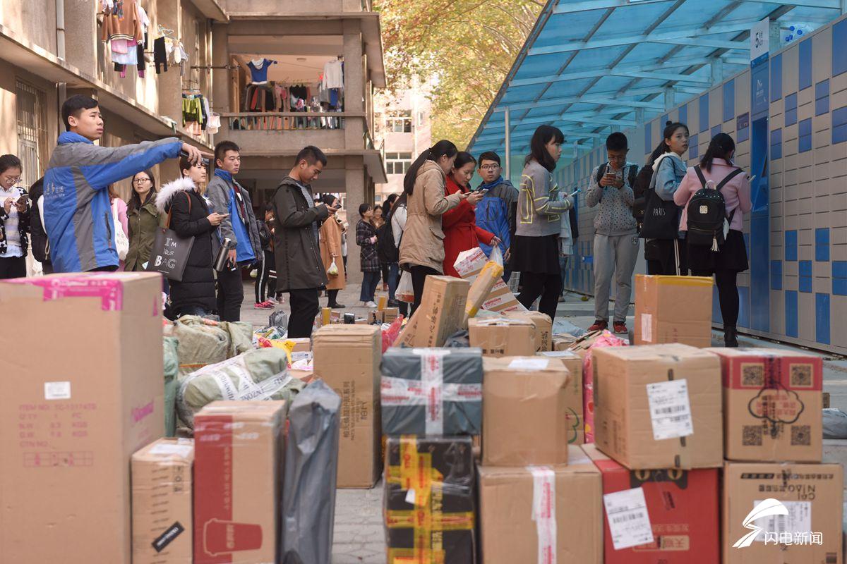 图为正在排队领取快递的学生,和正在紧张向快递箱里放包裹的快递员.