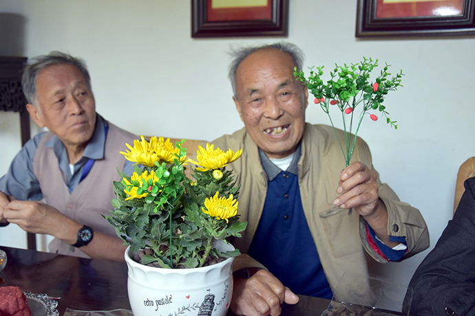 社区老人在展示制作的茱萸花卉。IC 资料图