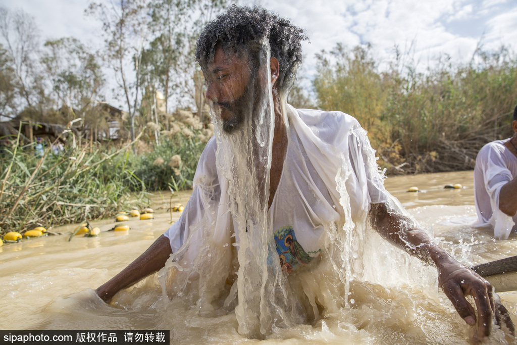 约旦河西岸朝圣者在泥水中受洗庆祝主显节