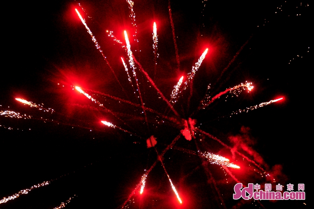 红色的礼花在夜幕中炸开的瞬间,划出相互交织的美丽弧线.