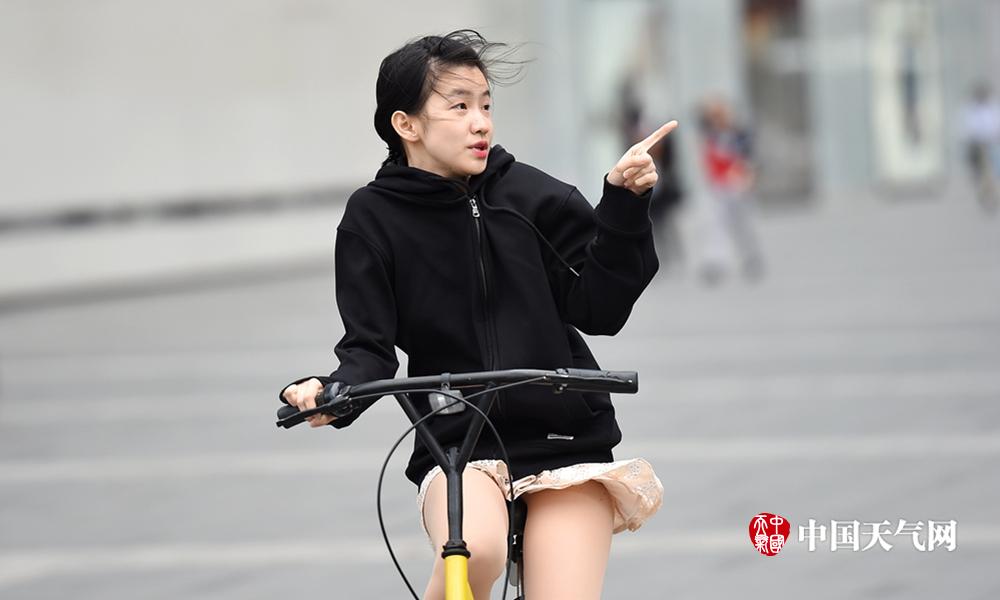 4月24日,四川省成都市气温非常低,还刮起了大风,美女街头"迎战"大风.